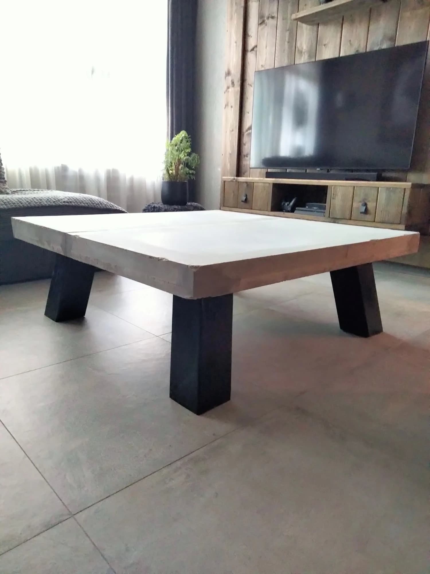 Salontafel met betonlook blad en zwarte houten poten