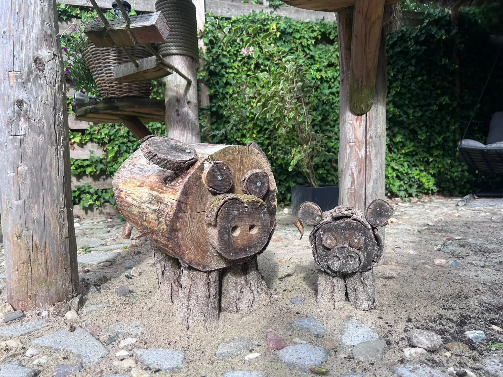 Twee varkentjes gemaakt van boomstamdelen in de tuin